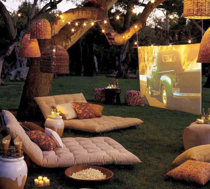 outside theater white cushions on the grass white screen lanterns fairy lights hanging from tree backyard ideas on a budget