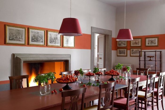 red wooden table and chairs modern farmhouse dining room next to fireplace art hanging on the wall