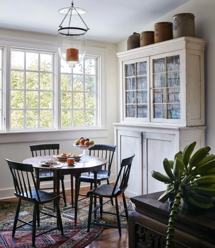 round table with vintage chairs and cupboard next to it dining room table decor ideas mismatched rugs