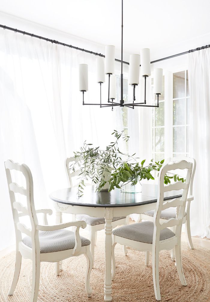 salvaged wood chairs and farmhouse kitchen table chandelier hanging above it