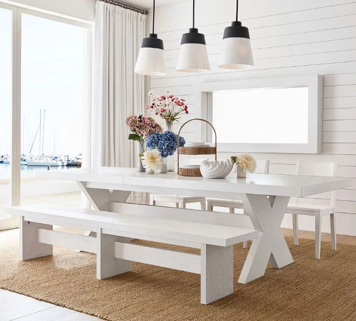 shiplap on the wall tall window modern farmhouse dining room white wooden table with bench and three chairs around it