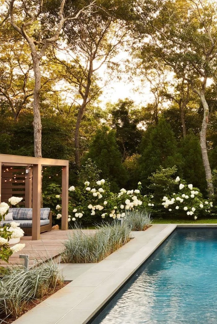 small backyard patio ideas large pool pergola with lounge area fairy lights surrounded by lots of trees white flowers