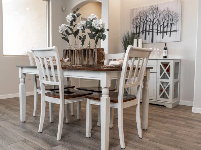 white chairs around table next to white cupboard modern farmhouse dining room flower bouquet on the table