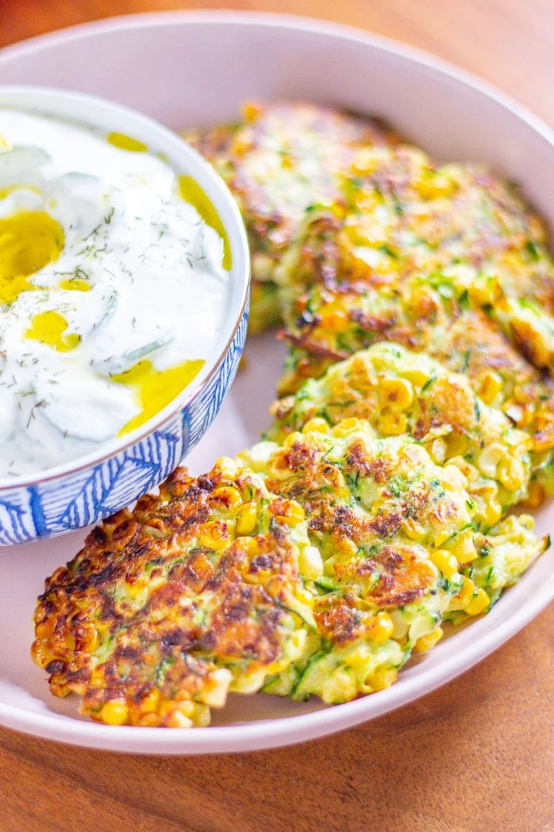 zucchini fritters recipe in white bowl with sauce