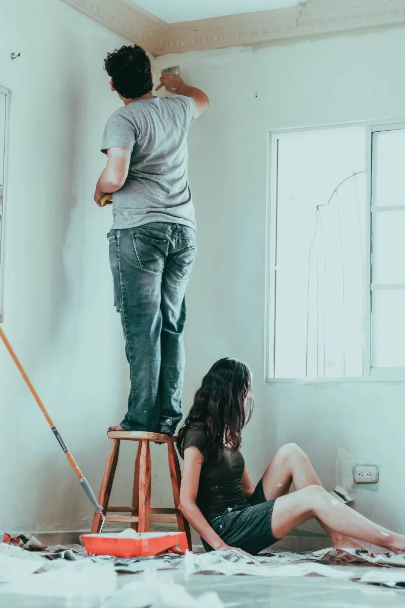 man on chair painting wall home improvements woman sitting on floor