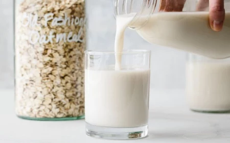 milk poured into glass homemade oat milk oats in jar