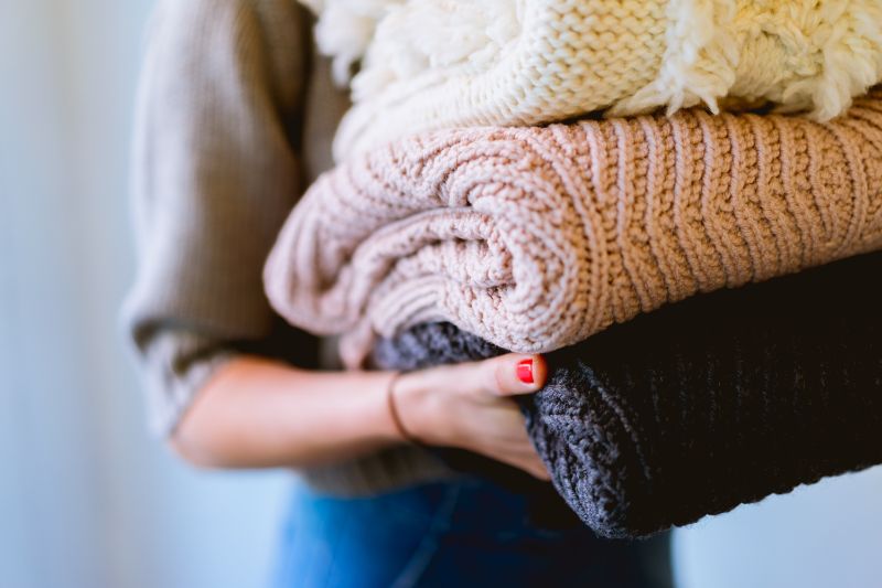 three sweaters learn to knit held by woman