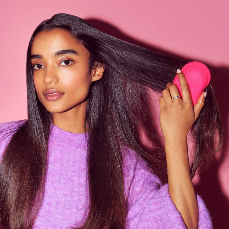 beautiful girl using hair brush to comb through long hair