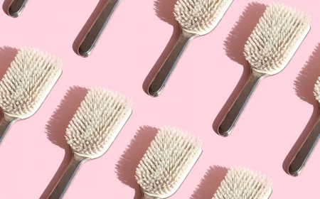 close up of repeated hairbrushes on pink background