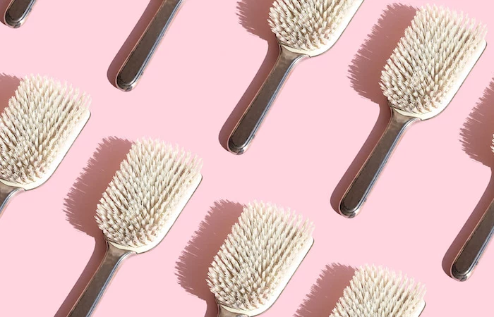 close up of repeated hairbrushes on pink background
