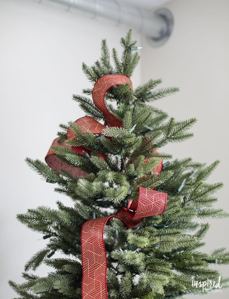 decorating christmas tree with ribbon in red