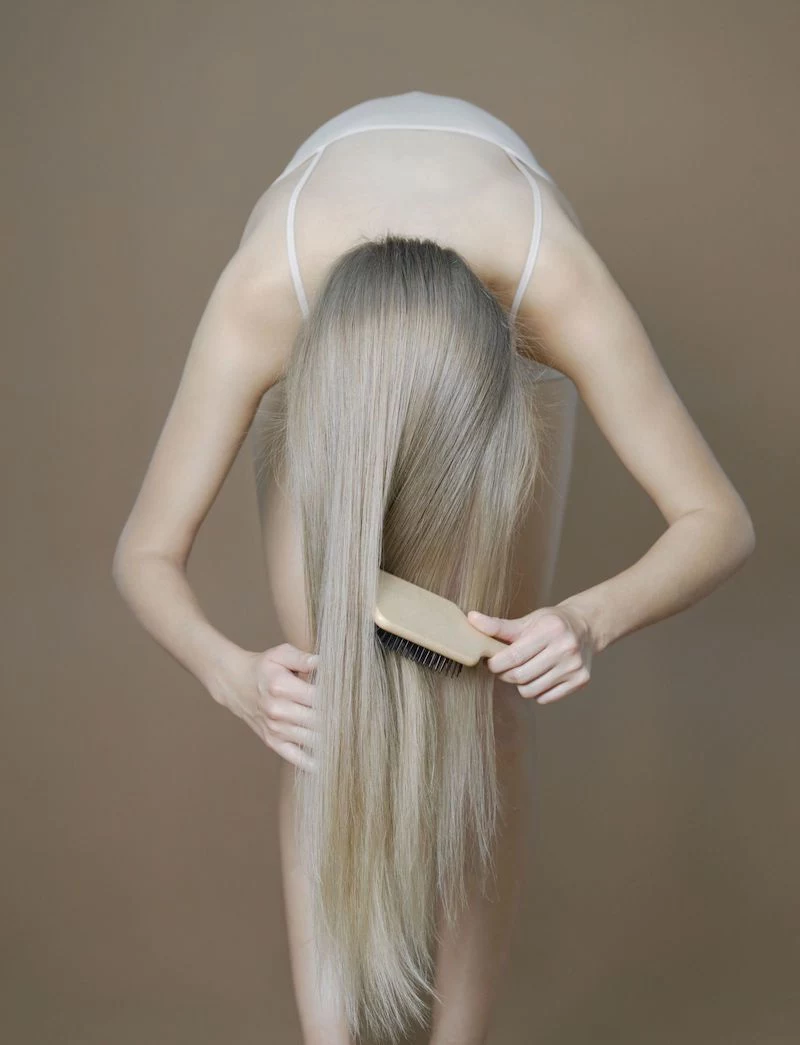 girl using wooden hair brush to comb hair upside down