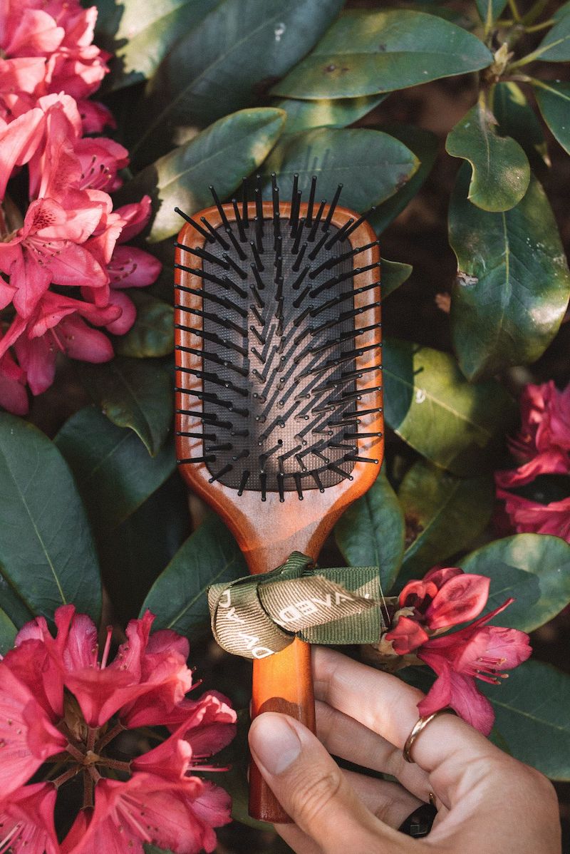 hair brush with wooden handle on a background with pink flowers