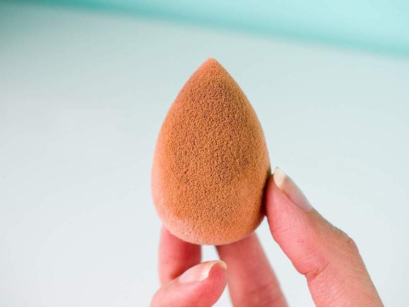 holding dirty pink beauty blender in hand