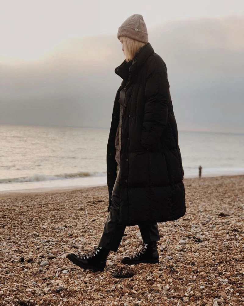 long black puffer jacket chunky boots on the beach