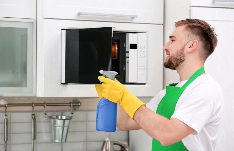 man cleaning how to clean microwave with gloves