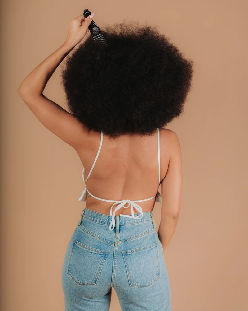 pretty girl using an afro pick to keep hair in shape