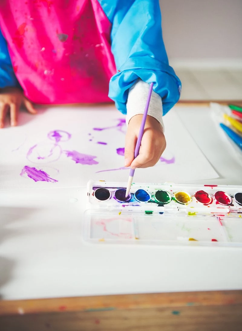 child's hand painting using watercolors