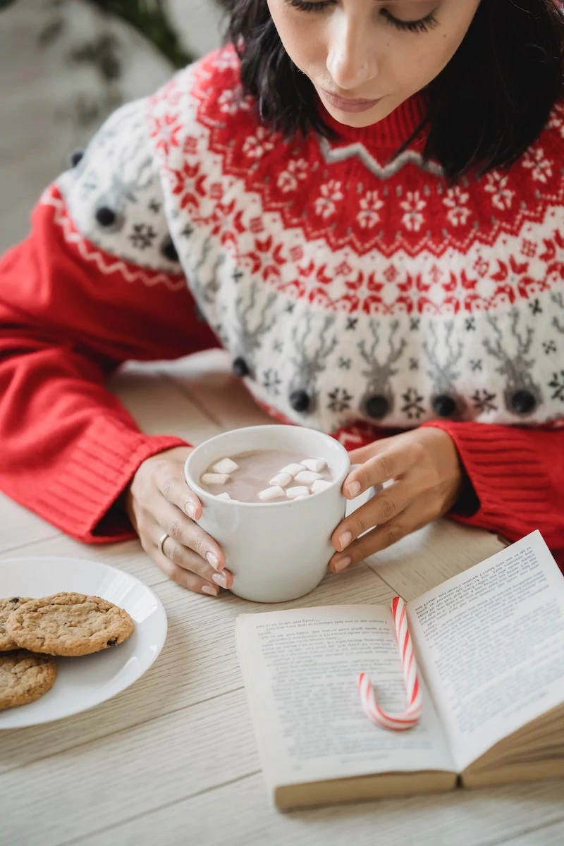 warm christmas drinks girl with red sweater enjoying hot chocolate candy cane
