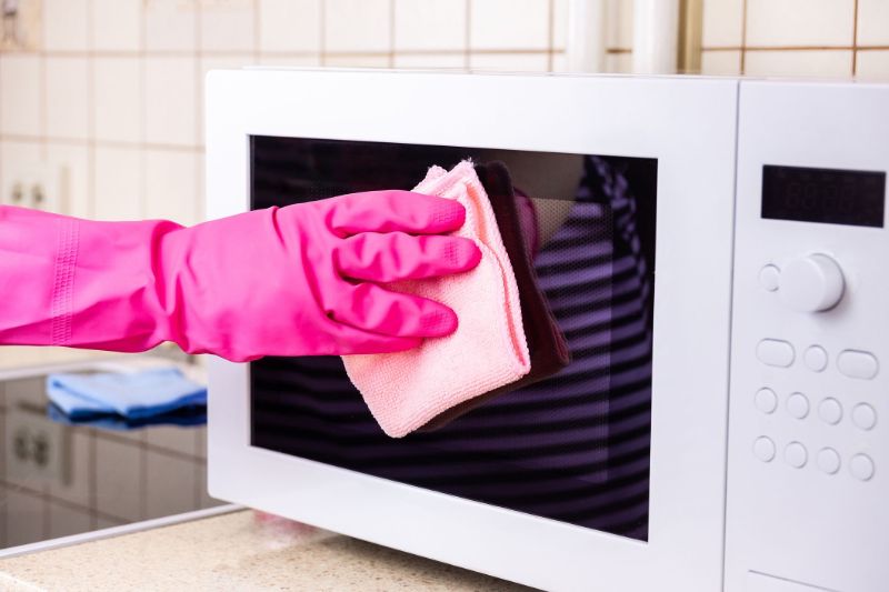 wiping the window of clean microwave with lemon