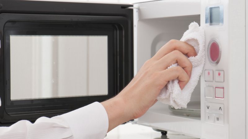 wiping with towel clean microwave with vinegar
