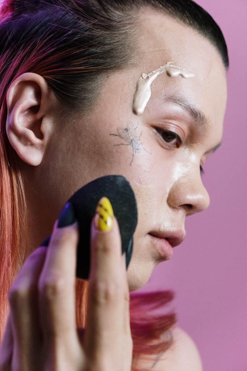 woman applying foundation with beauty blender over tattoos