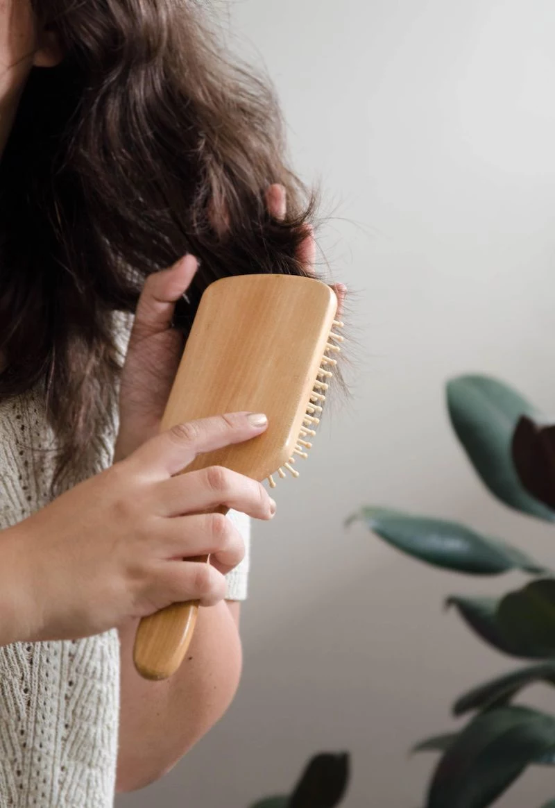 woman combing her hair with big wooden hair brush