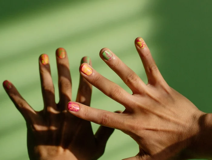 nail inspo hand on green background wiht colorful nails