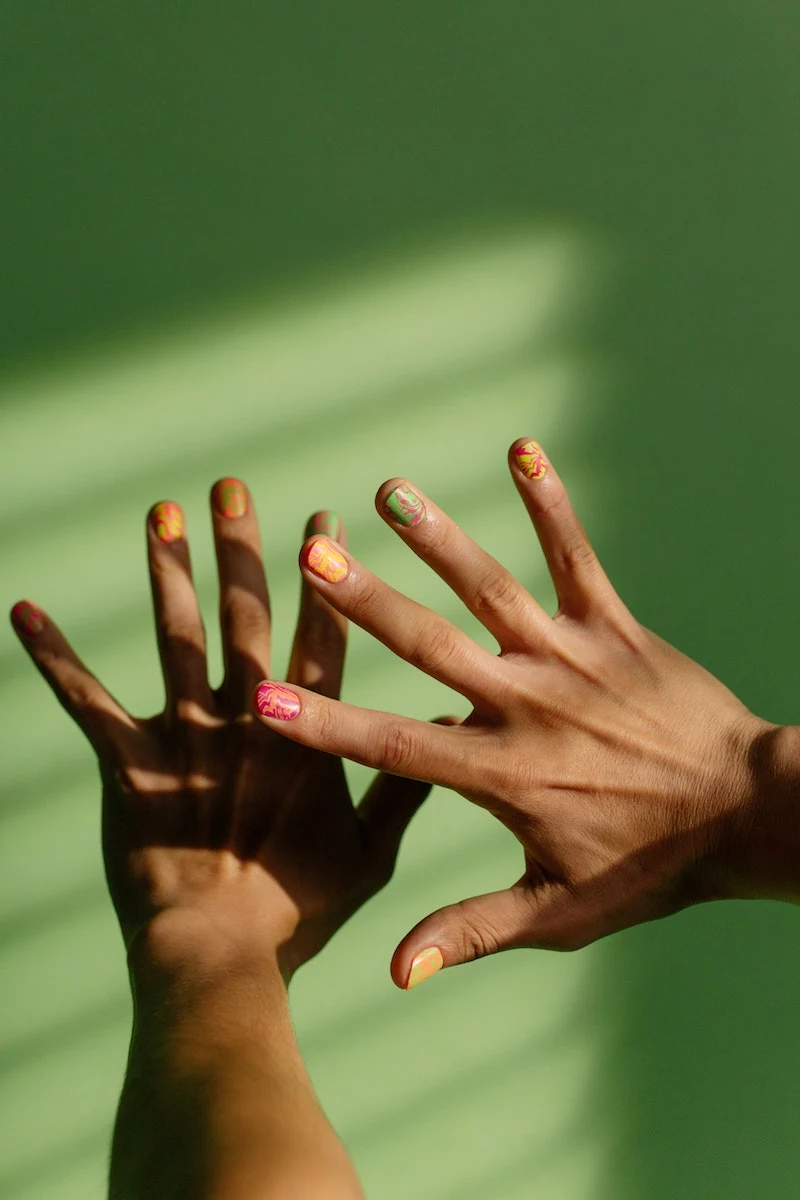 nail inspo hand on green background wiht colorful nails