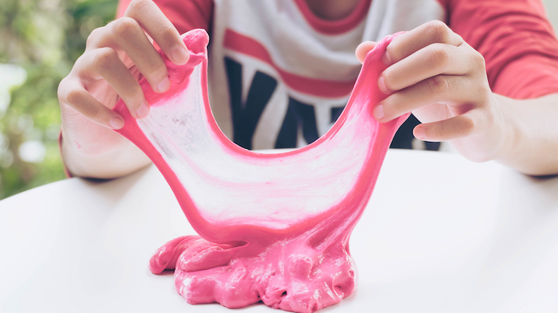hand holding homemade plaything called slime, teenager having fun and being creative homemade toy, selective focus on slime.