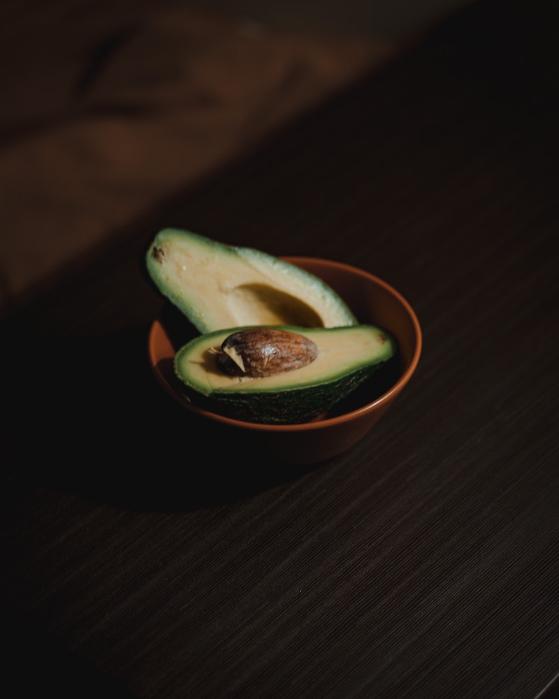 a sliced avocado in a wooden bowl