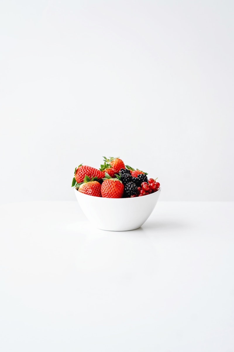a white bowl full of stawberries and other berries