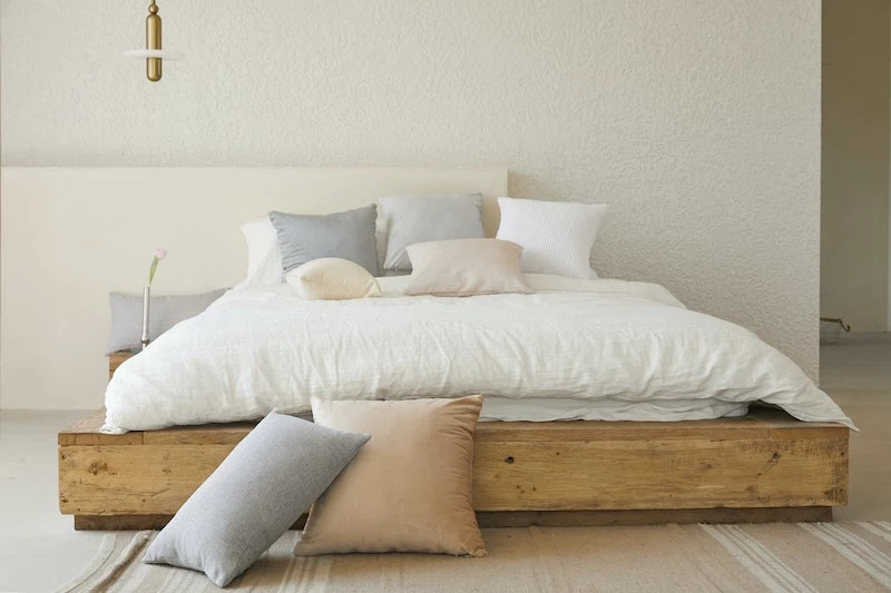 big bed with white bedding and beige pillows