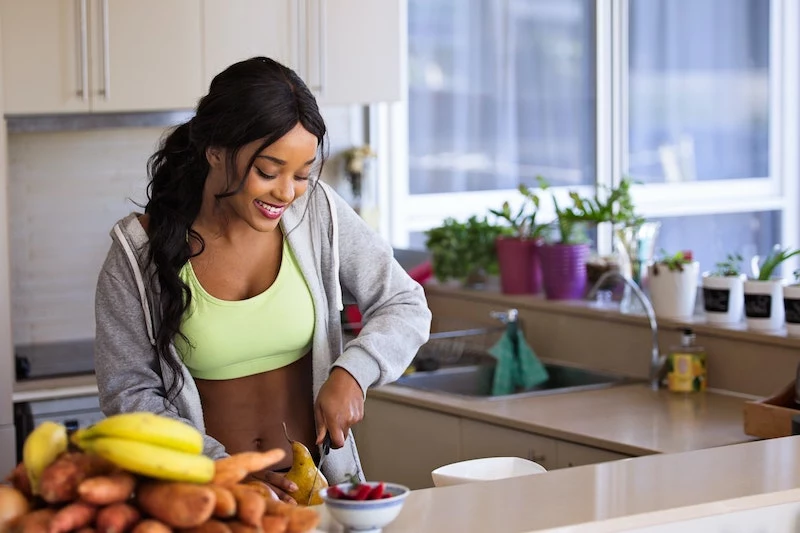 black woman in green top preparing healthy snack