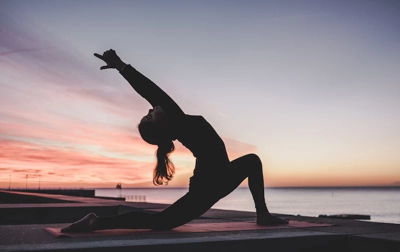 exercise for weight loss woman doing yoga in front of sunset