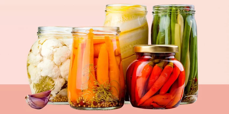 fermented foods in big jars on pink background