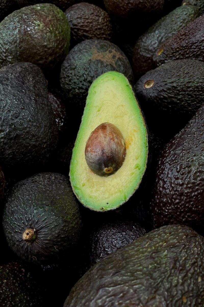 foods that burn belly fat a halved avocado with pit on top of other avocados