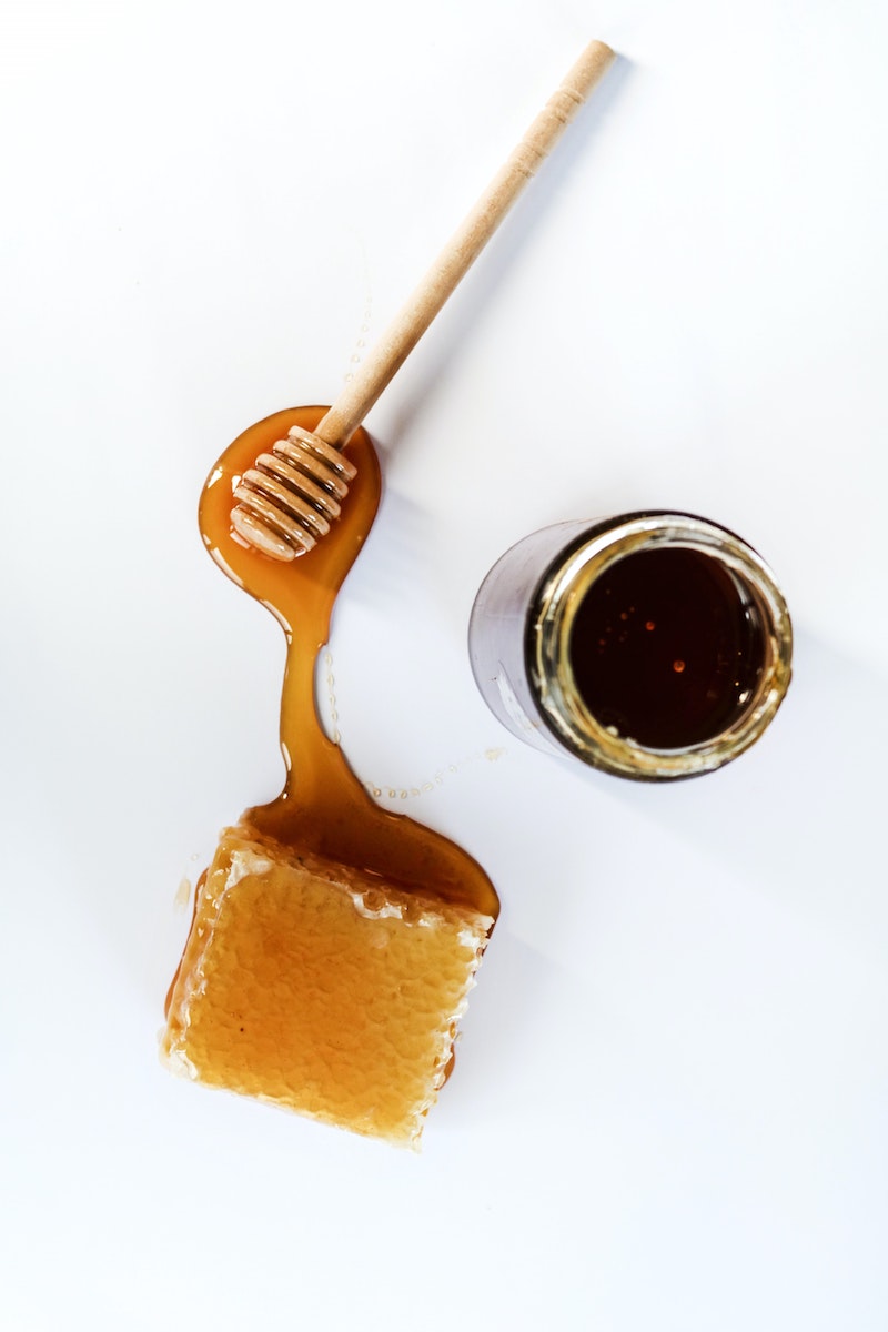 honeycomb jar of hone and spoon on white background