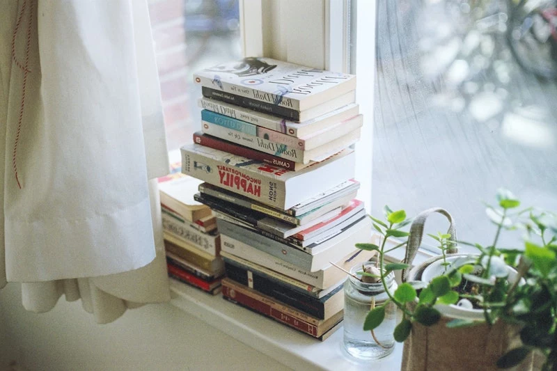 how to declutter your home books stacked on a window sill