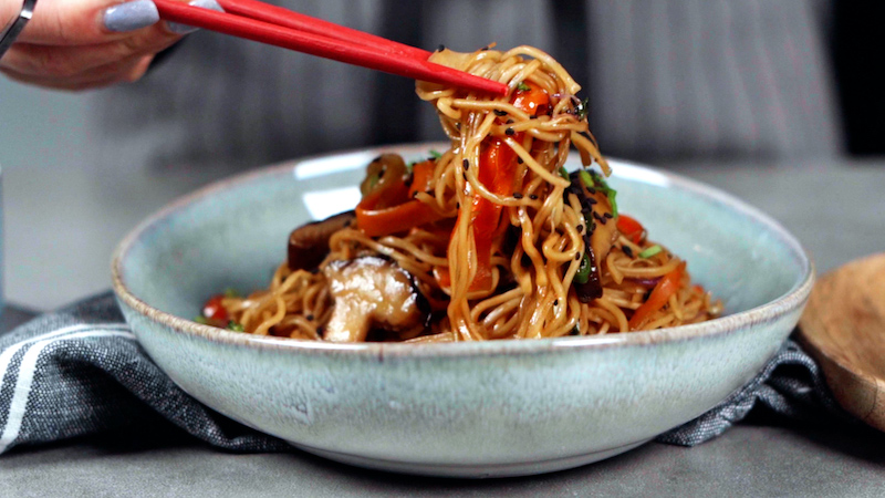 noodles being picked up with red chopsticks