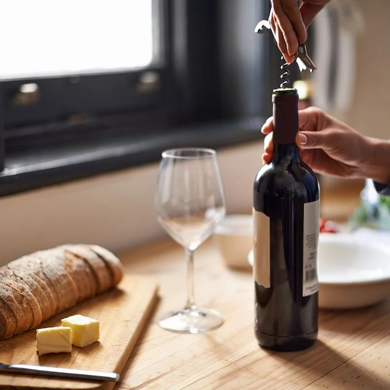 ow to declutter your home person opening a cork red wine bottle