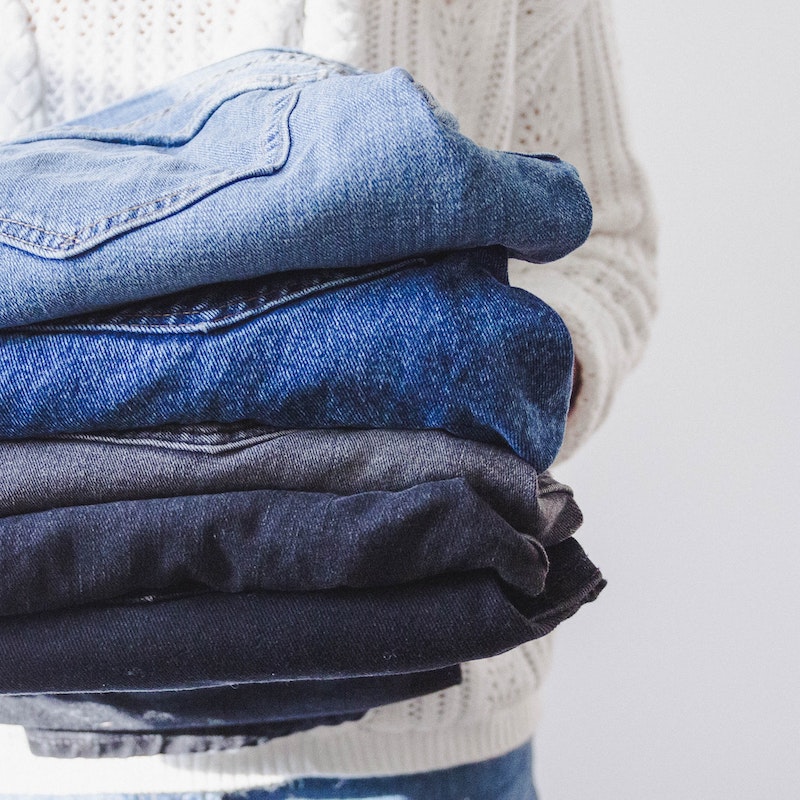 person holdin a pile of different jeans