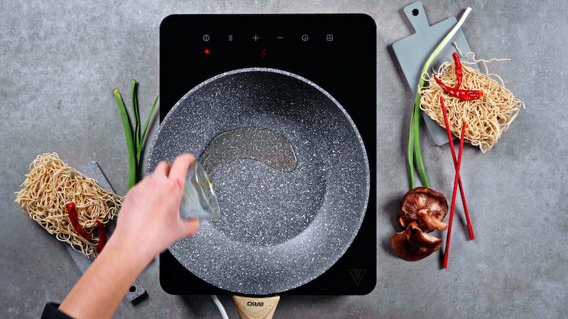l'olio di sesamo viene aggiunto in un wok grigio