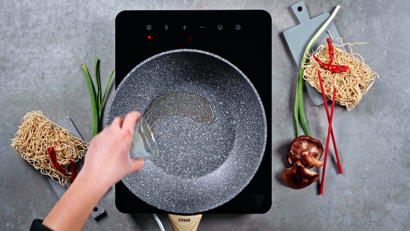 sesame oil being added into a gray wok