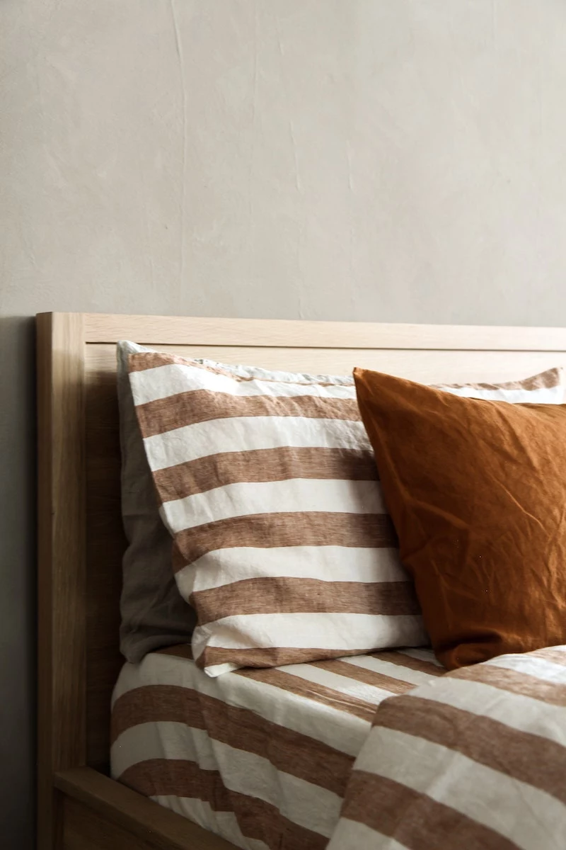 stripe beige pillow and redish pillow on a bed