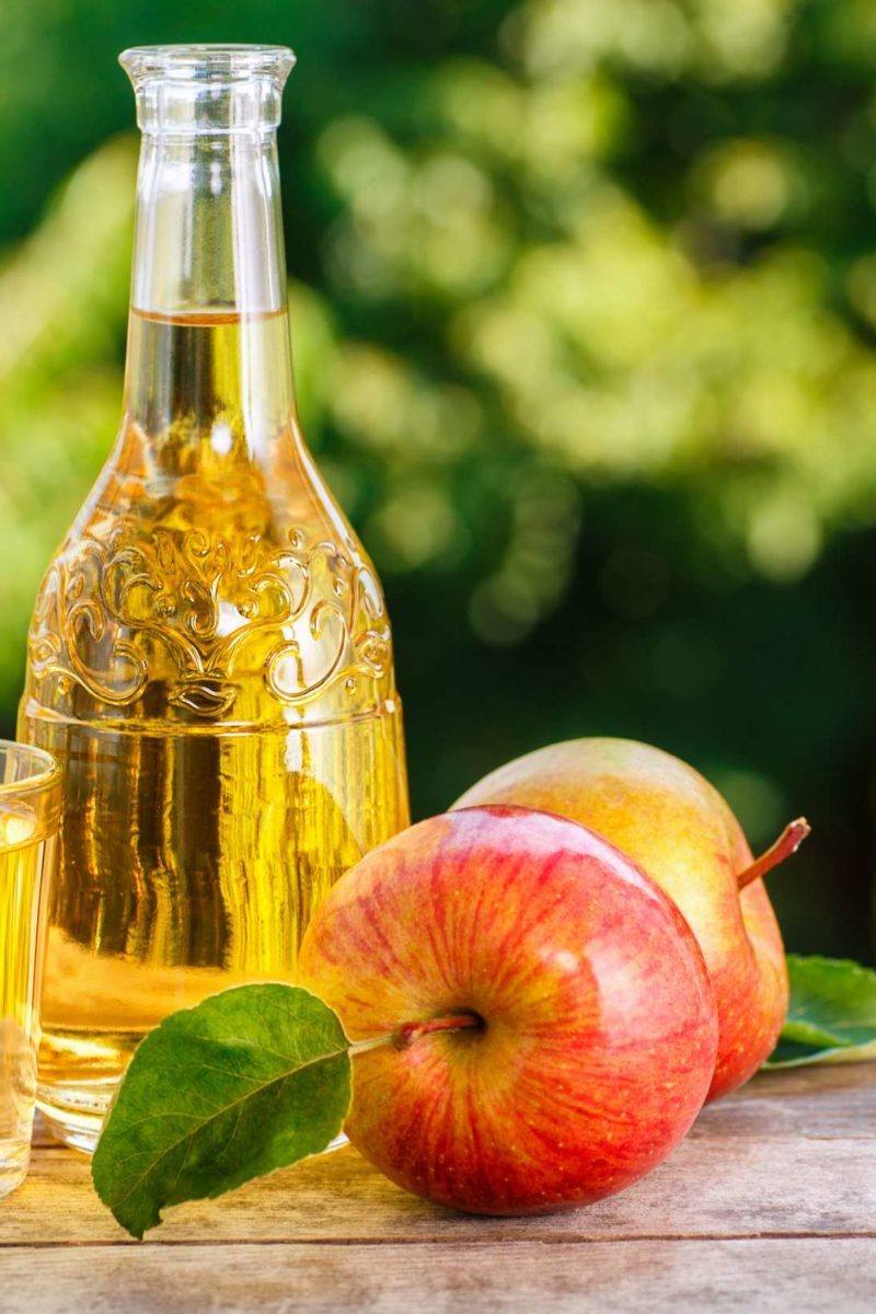 vinegar in glass container with apple in front