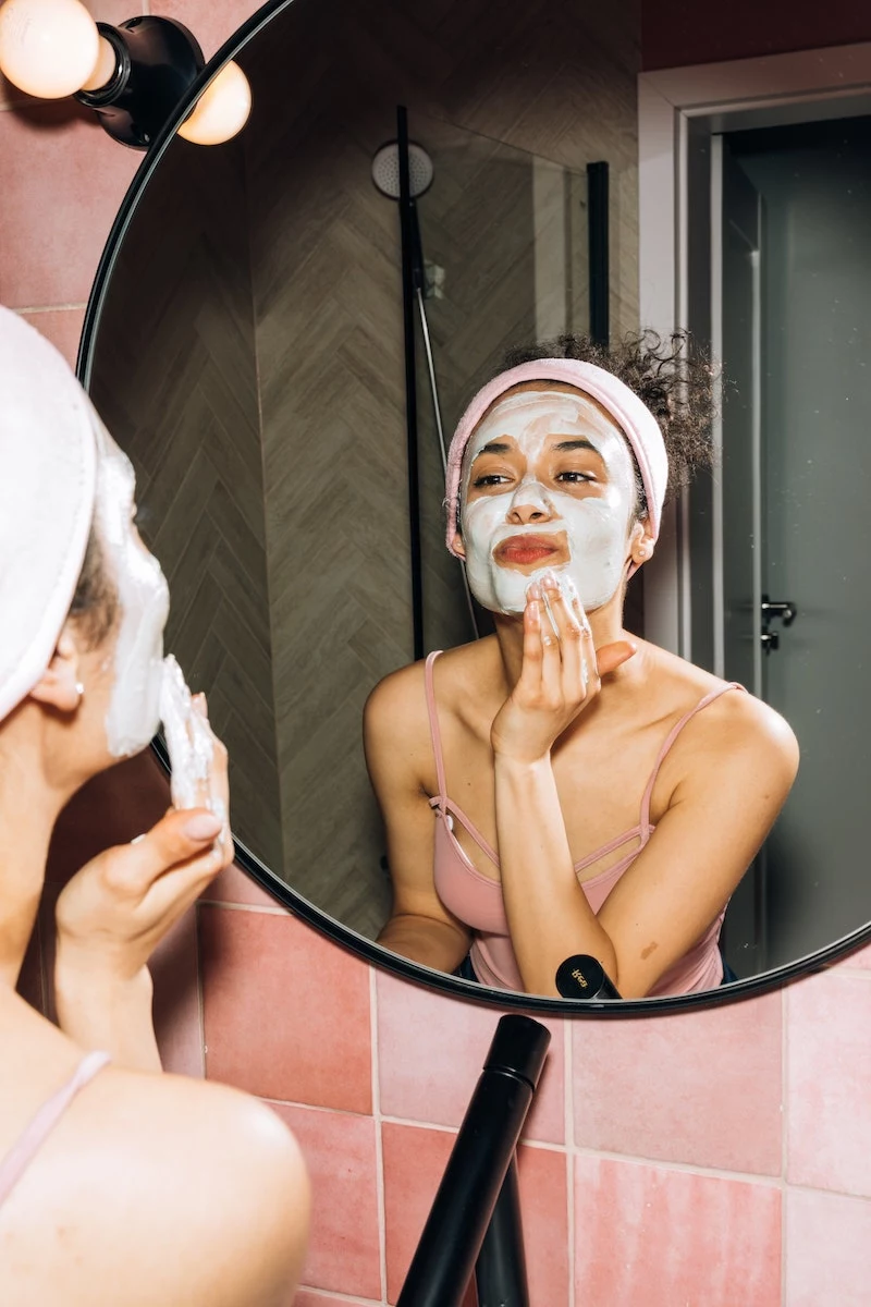 woman doing her skincare with green mask on