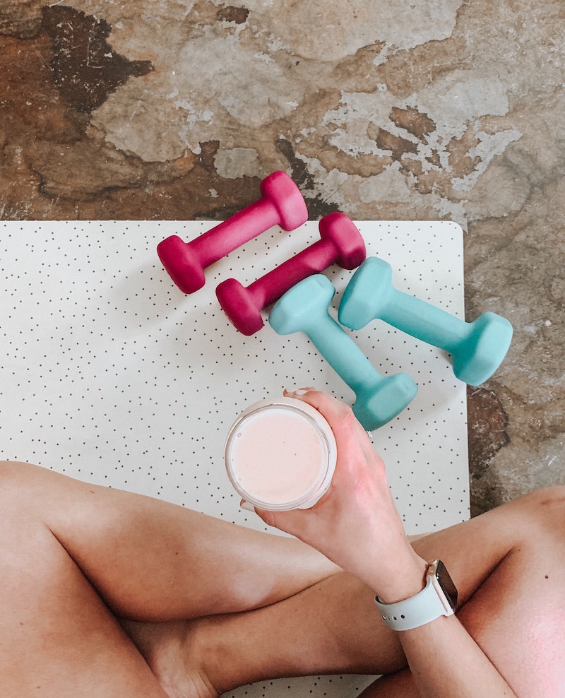 woman holding a smoothie on a work out mat
