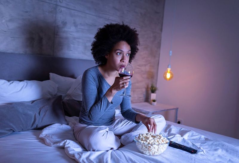 woman in front of tv eating popcorn late at night