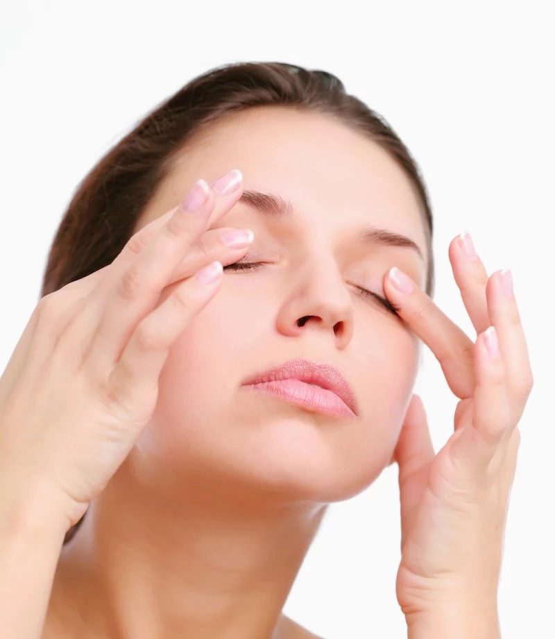 young woman pushes with fingers on closed eyes. isolated over white.